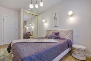 white bedroom with bed with purple comforter and mirror closet doors